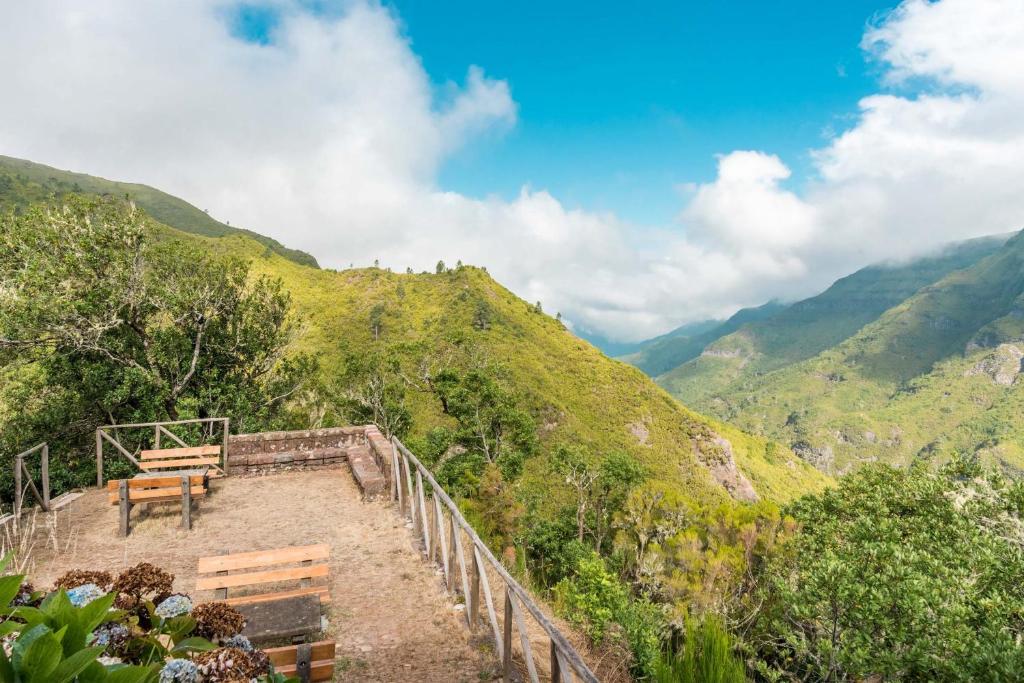 un banco al lado de una colina con montañas en Rabaçal Nature Spot Cottage en Estreito da Calheta