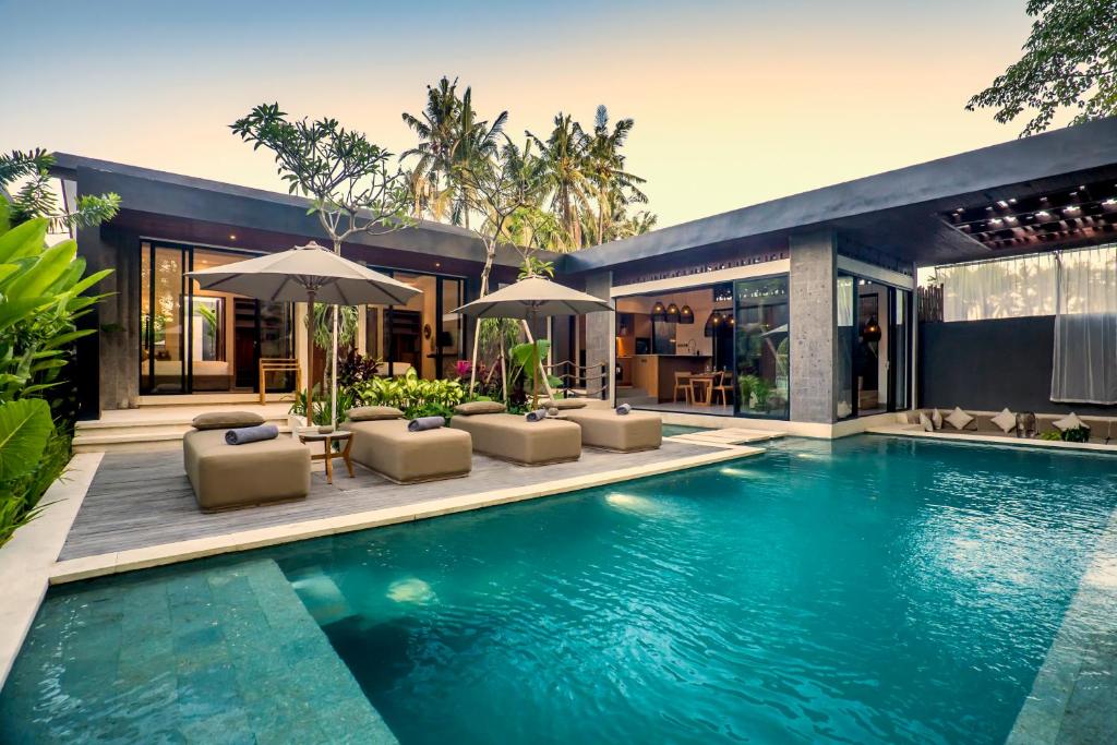 - une piscine avec des chaises et des parasols à côté d'une maison dans l'établissement Sarang Cocoon Villa Ubud by BaliSuperHost, à Ubud