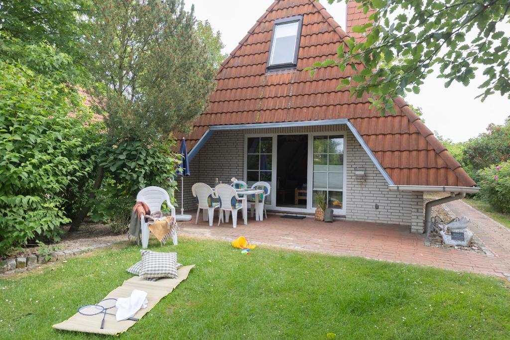 ein Haus mit einem Tisch und einem Hund im Hof in der Unterkunft VS 7 - Strandvogt Standard in Dorum Neufeld