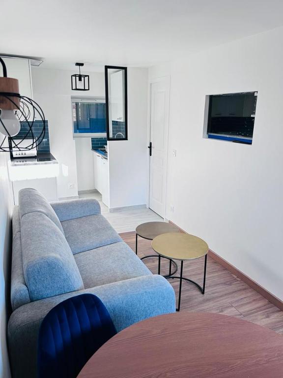 un salon avec un canapé bleu et une table dans l'établissement Cosy home proche de Roissy CDG PARIS, Parc Astérix I Aéroville I Parc des Expo I Villepinte, à Louvres