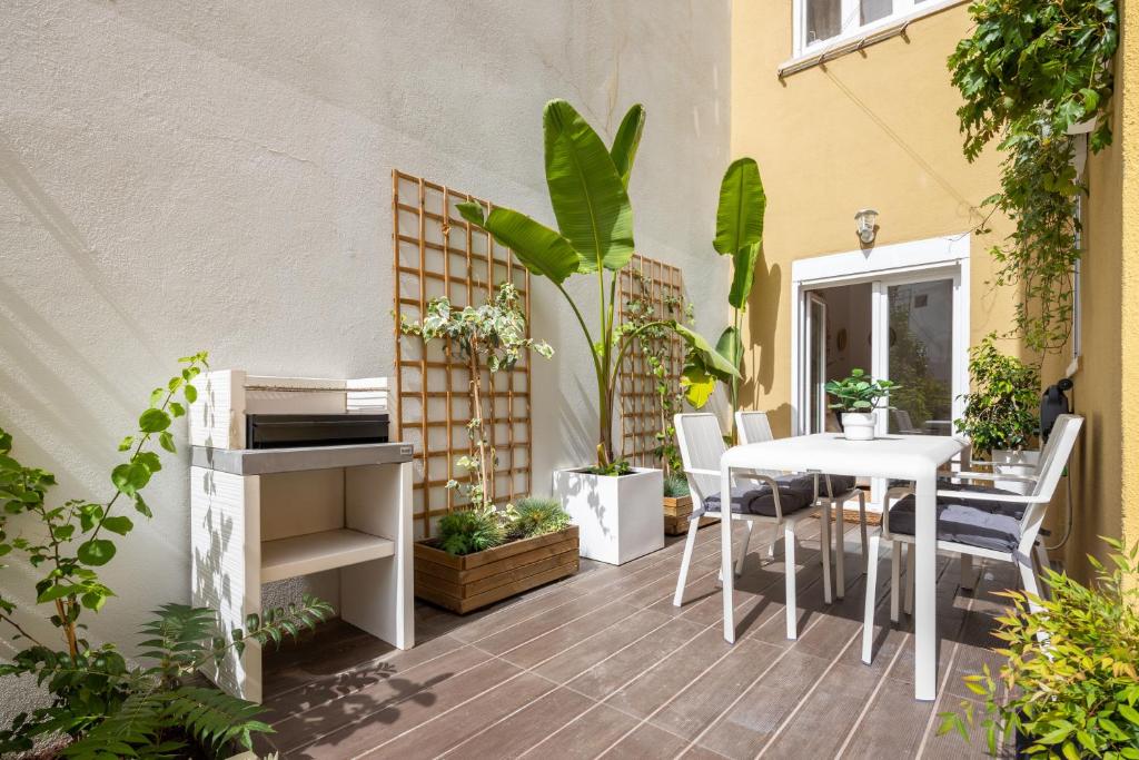 um pátio com uma mesa branca, cadeiras e plantas em Serene 2BDR Apartment W/ Patio by LovelyStay em Lisboa