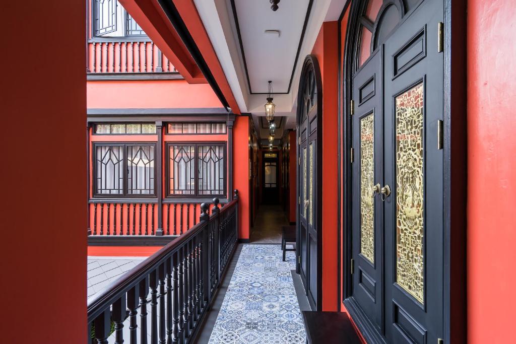 un couloir avec des murs rouges et orange et une porte dans l'établissement DE Phanakron Boutique Hotel, à Bangkok