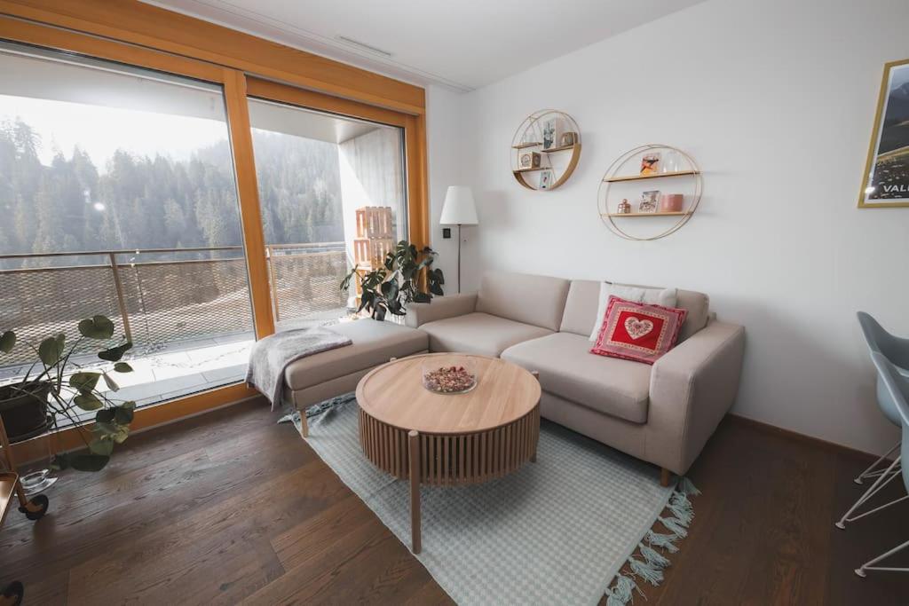 a living room with a couch and a table at Cosy, stylish new 2-bedroom flat with spa and gym in Laax