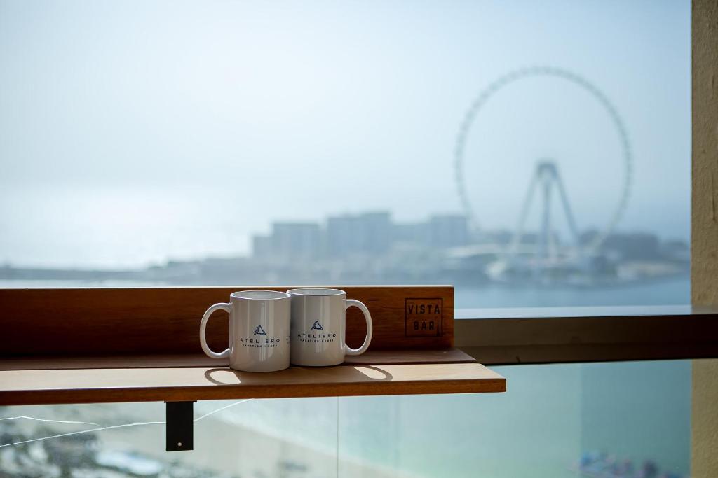 Duas canecas de café brancas no peitoril da janela. em Luxury 2BR at Rimal 3 em Dubai