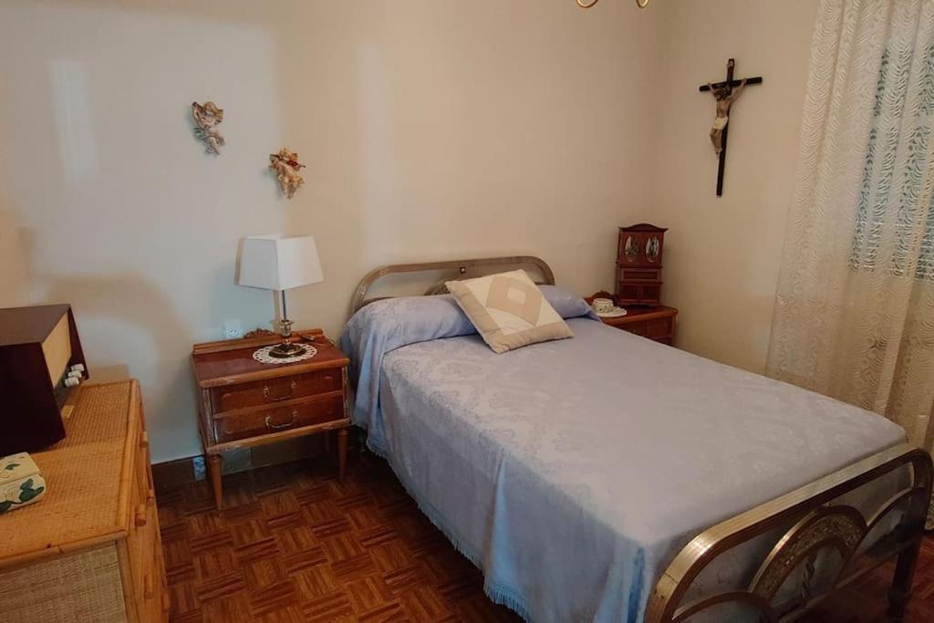 ein Schlafzimmer mit einem Bett und einem Kreuz an der Wand in der Unterkunft casa lucia in Palencia