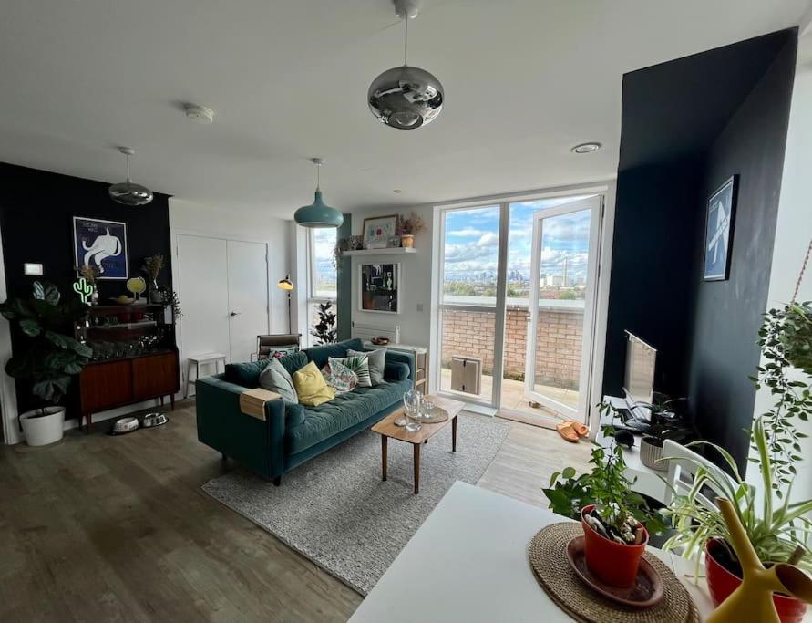 ein Wohnzimmer mit einem grünen Sofa und einem großen Fenster in der Unterkunft Elegant Chic Living: 1 Bed In Vibrant London Area in London