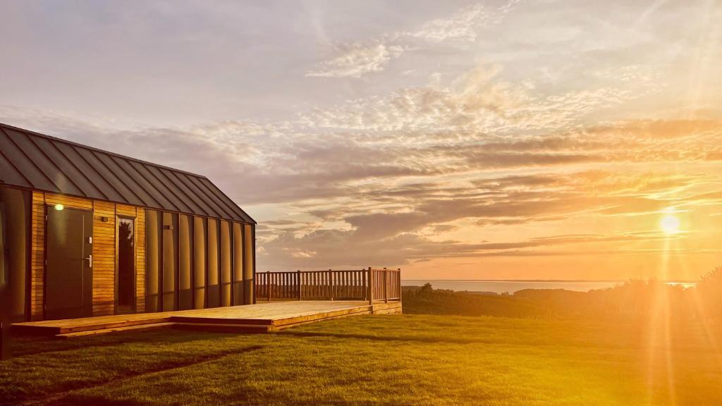 a house on a hill with the sun setting behind it at Osada nad Zalewem in Tolkmicko