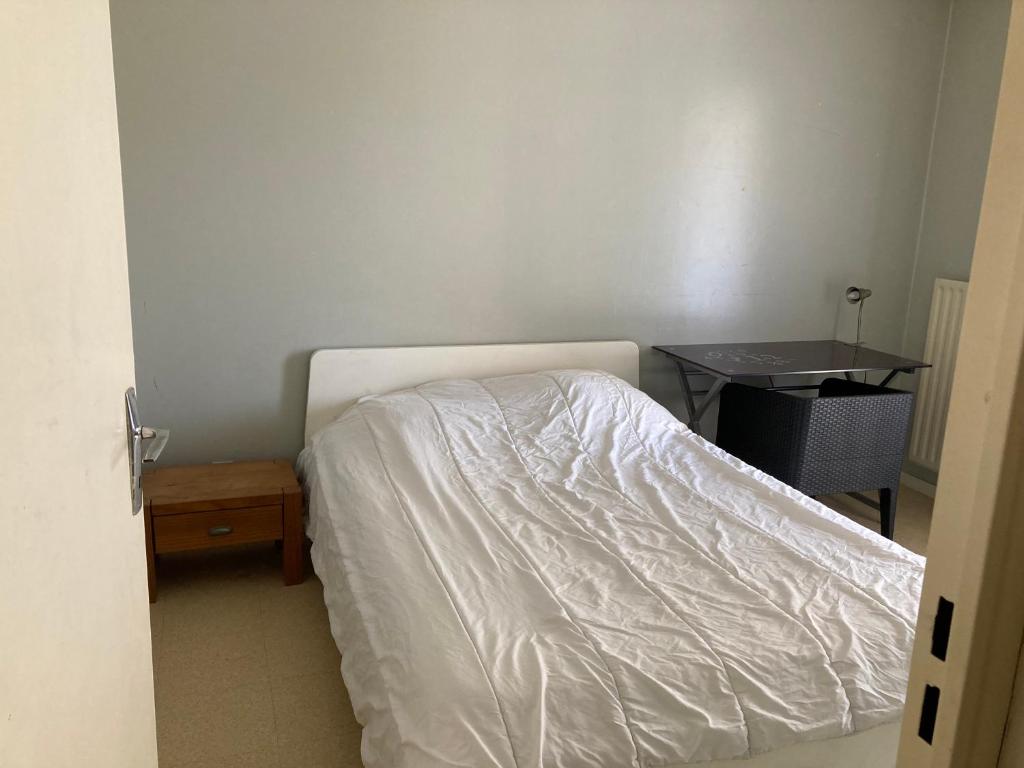 a bedroom with a white bed and a table at Chambre chez l'habitant à Lyon Centre in Lyon