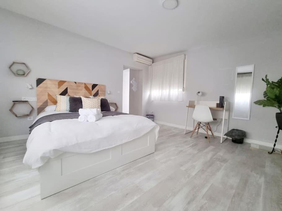 Un dormitorio blanco con una cama grande y un escritorio. en Increíble Apartamento de lujo en Triana, en Sevilla