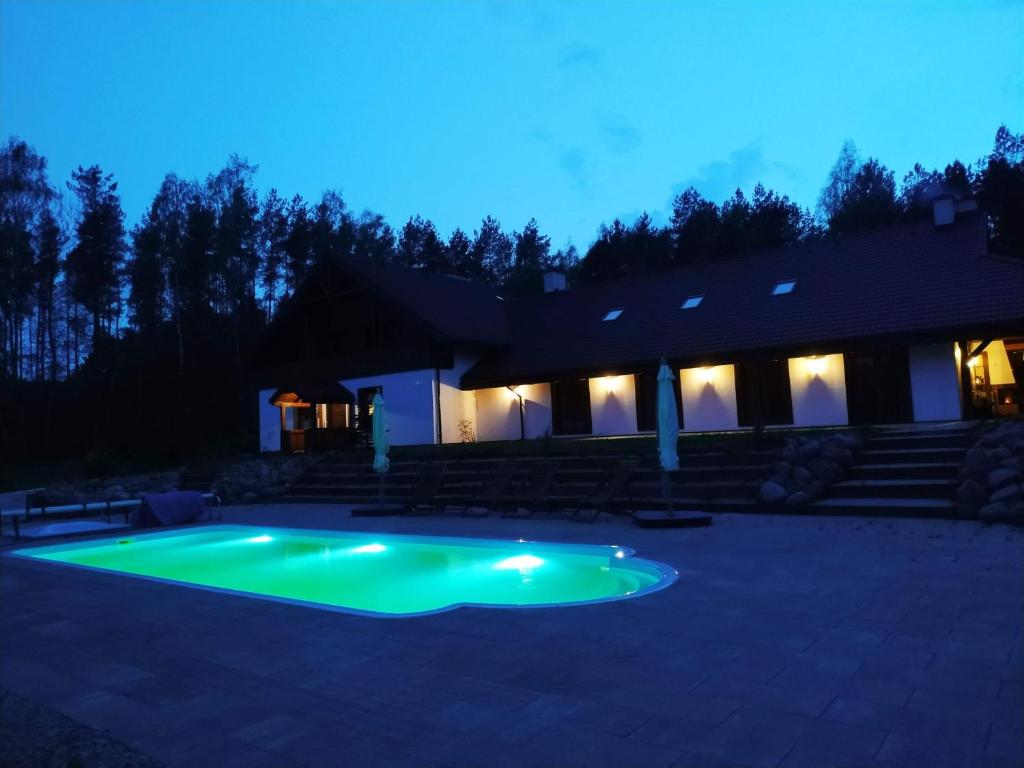 ein Swimmingpool vor einem Haus bei Nacht in der Unterkunft Domek przy Majątku Morgi in Suchowola
