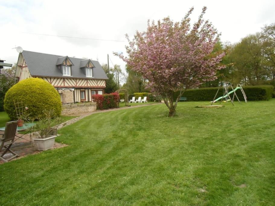 una casa con un patio con un árbol y un columpio en Gîte Les Ronces, en Conteville