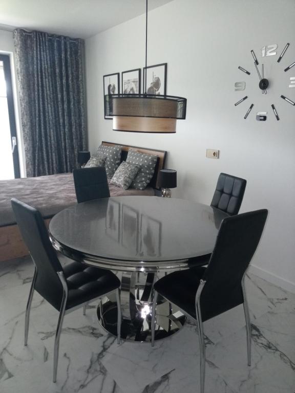 a dining room with a table and chairs and a clock at Apartament Bieszczadzka A 8 Lesko in Lesko