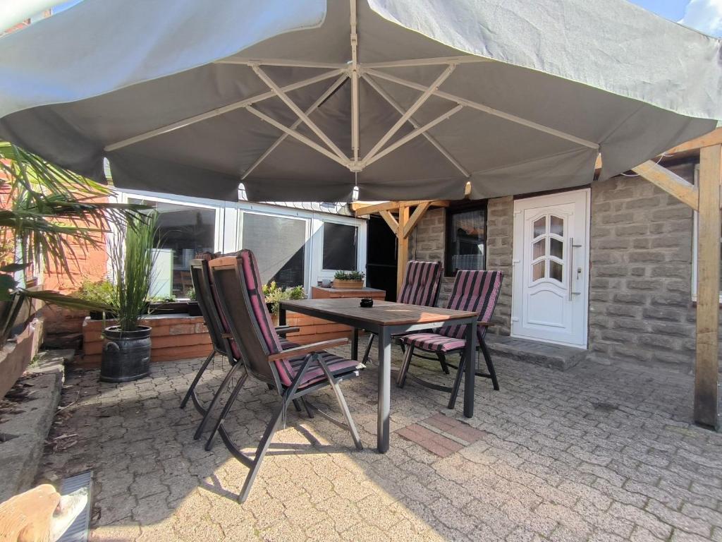 een tafel en stoelen onder een parasol op een patio bij Ferienwohnung Mohnkopf in Jerrishoe