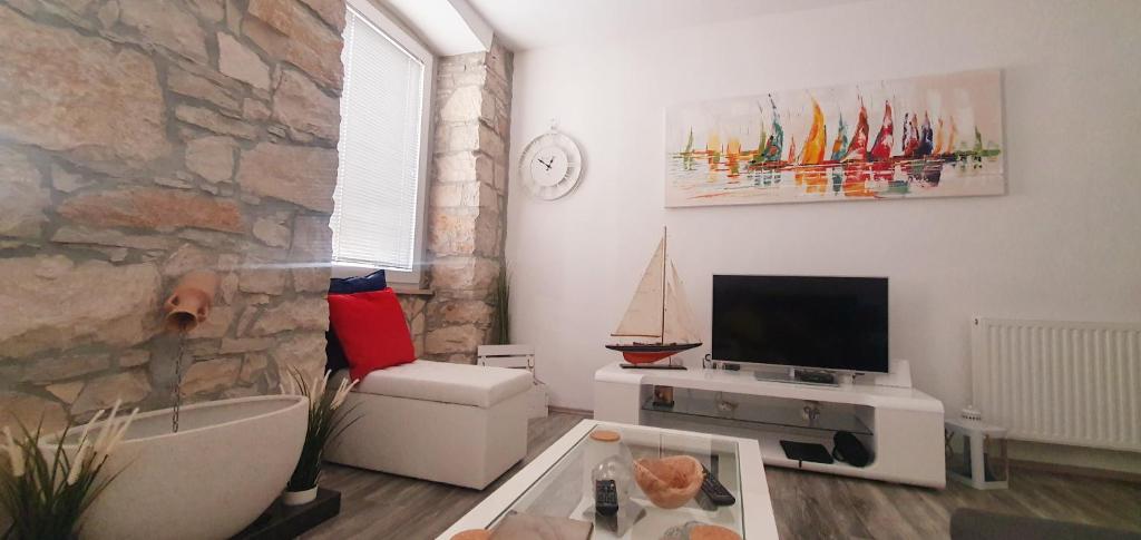 a living room with a tv and a stone wall at FORMOSA, The boutique apartment, City Center, Pula in Pula