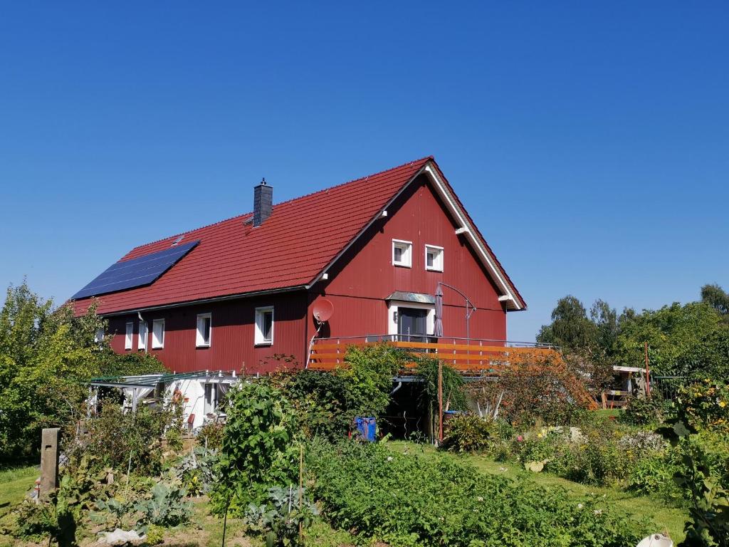 een rood huis met een rood dak op een heuvel bij Ferienwohnung Feldblick in Struppen