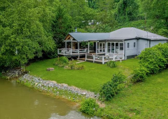 a house with a large yard next to a river at Mccaysville River House in McCaysville