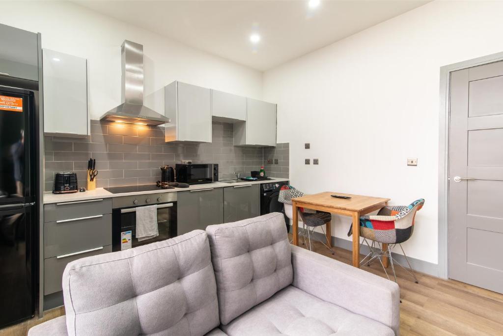 uma sala de estar com um sofá e uma cozinha em Charnwood Flat 4 - City Center 3BR Gem em Derby