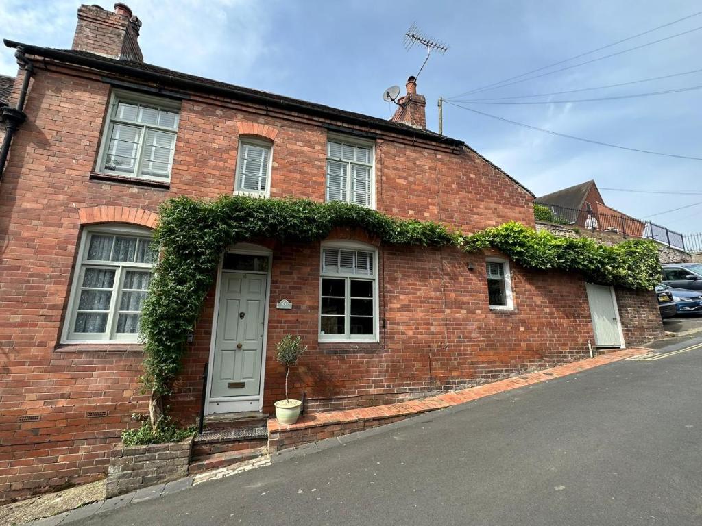 una casa de ladrillo rojo con hiedra creciendo en ella en The Railway Cottage Bridgnorth en Bridgnorth