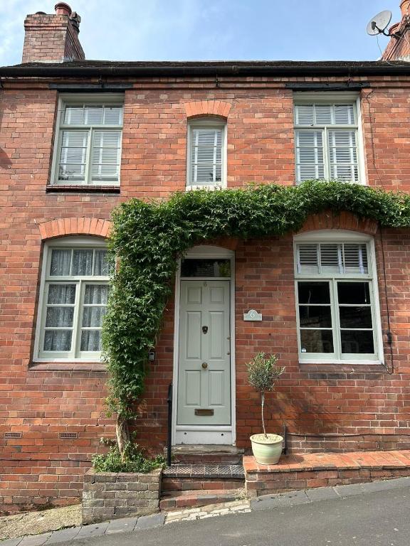 a brick house with a green door and two windows at The Railway Cottage Bridgnorth in Bridgnorth