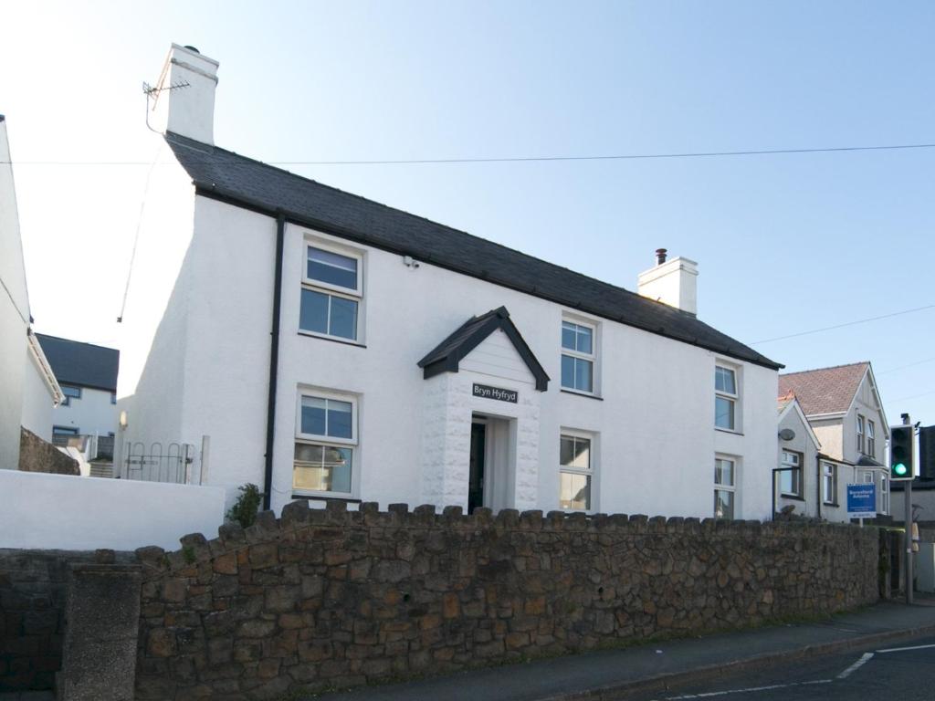 a white house with a stone wall at Pass the Keys Spacious Cottage in central Benllech with parking in Benllech