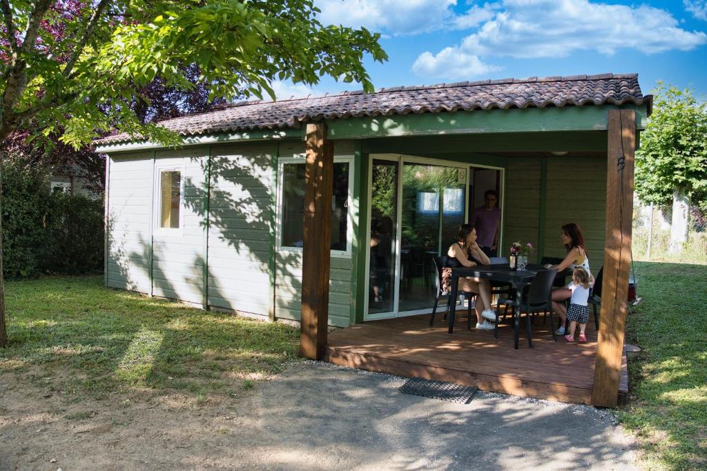een gezin aan een tafel op een terras in een achtertuin bij Les chalets de Gaillac in Gaillac