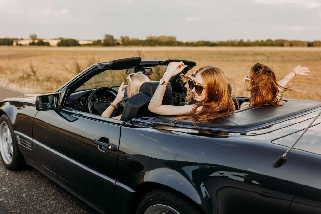 two women in a convertible car on a road at Wellness Apartment, Spa i Sauna 