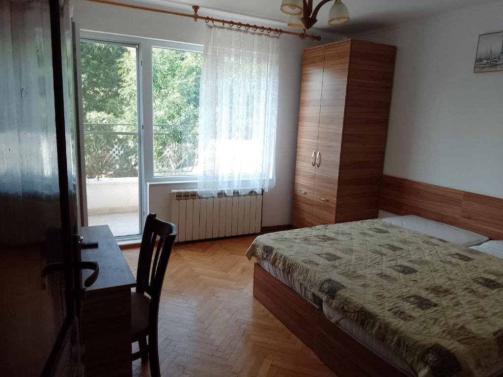 una camera con letto, scrivania e finestra di Цвят бяло a Sofia