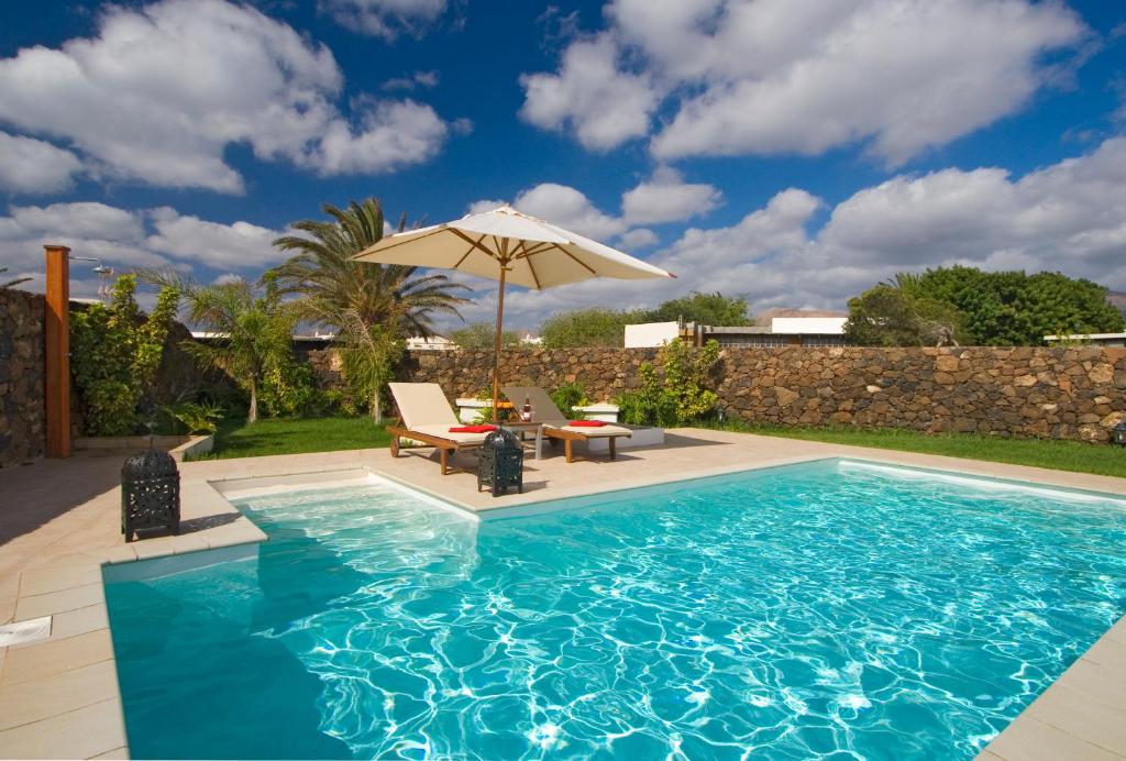 uma piscina com um guarda-sol, uma mesa e cadeiras em Beautiful Villa Ambar em Puerto del Carmen