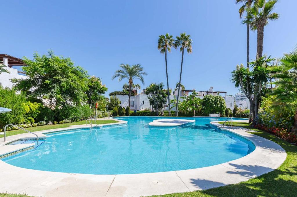 a swimming pool with palm trees in a resort at Escape to Serenity - 3 Bedroom Townhouse by the Sea! in Marbella