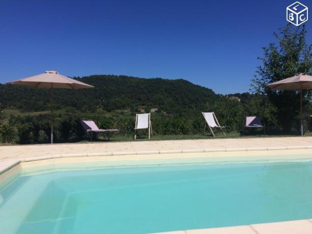 Silhac的住宿－Villa la bastide piscine et jacuzzi，一组椅子和遮阳伞,位于游泳池旁