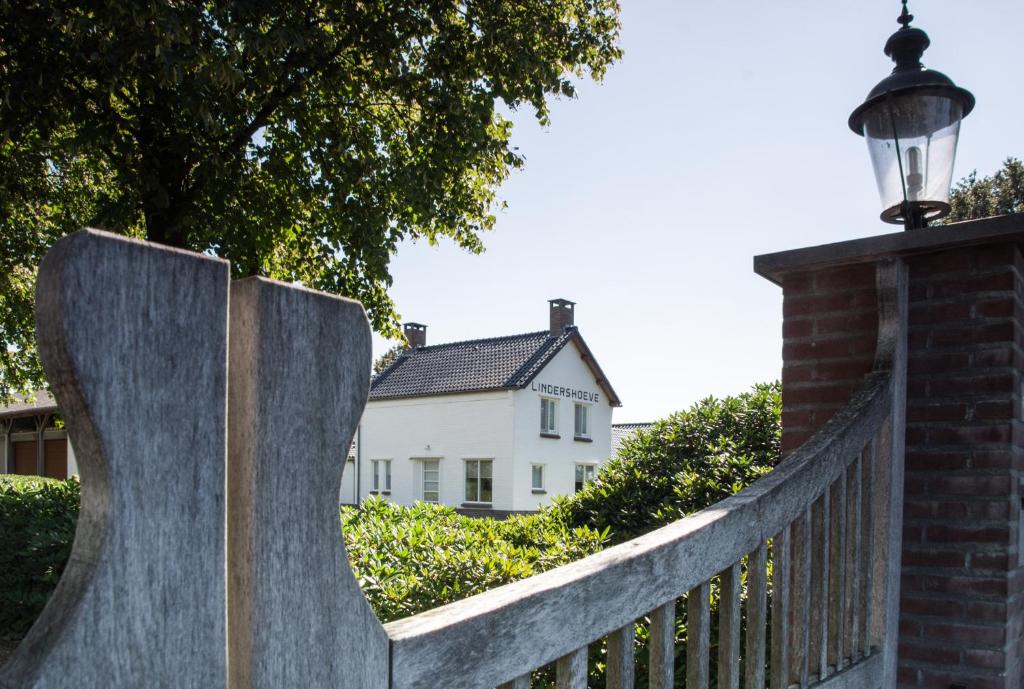 a fence with a white house in the background at Bed and Breakfast Lindershoeve Bergeijk in Bergeijk