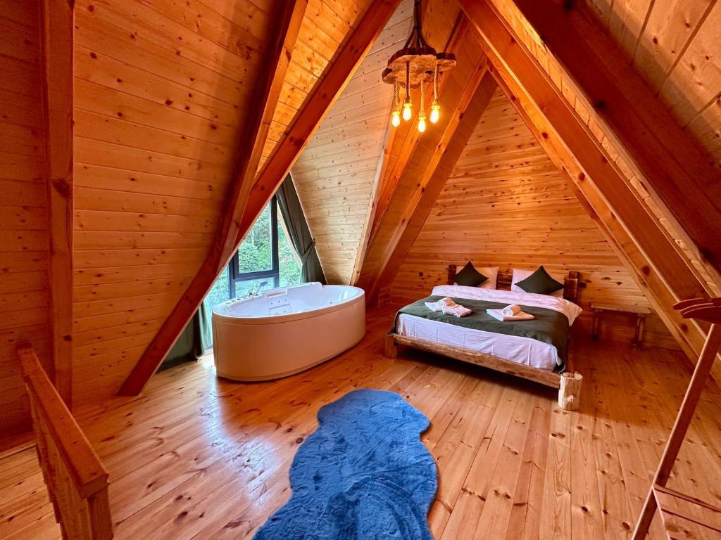 Moni Suit Bungalov في ريزي: غرفة مع سرير وحوض استحمام في العلية