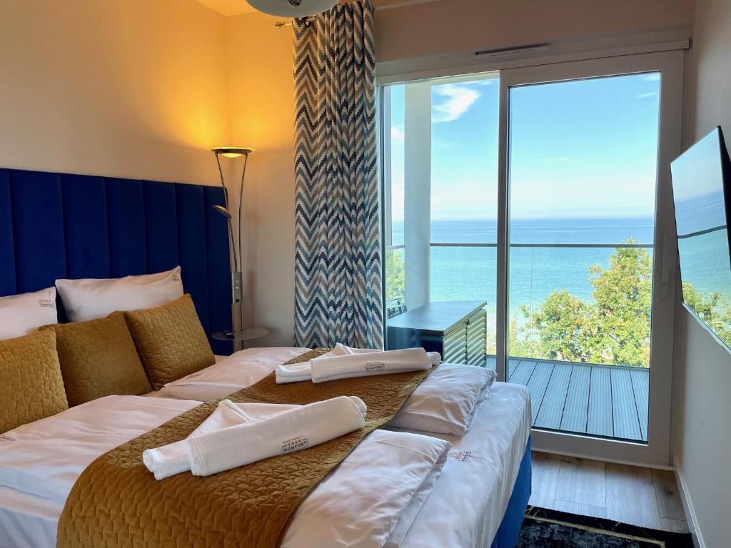 een hotelkamer met een bed en uitzicht op de oceaan bij Perlowa Przystan - Apartamenty KOMFORT widok na morze, parking in Sianozety