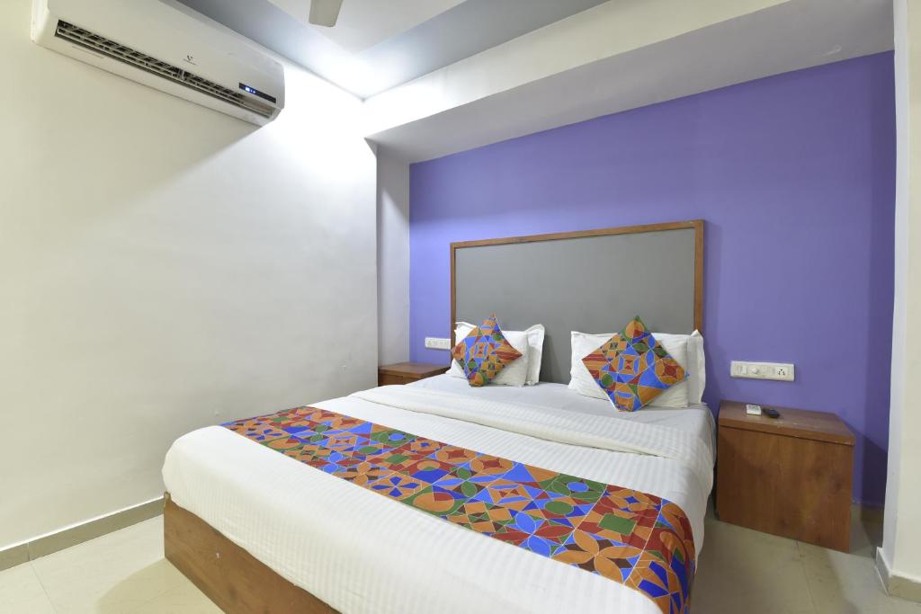 um quarto com uma cama grande e uma parede roxa em HOTEL GOLD LEAF em Ahmedabad