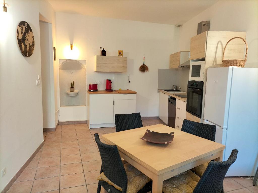 eine Küche mit einem Tisch und Stühlen sowie einem weißen Kühlschrank in der Unterkunft Entre Voyages et Occitanie in Vers-Pont-du-Gard