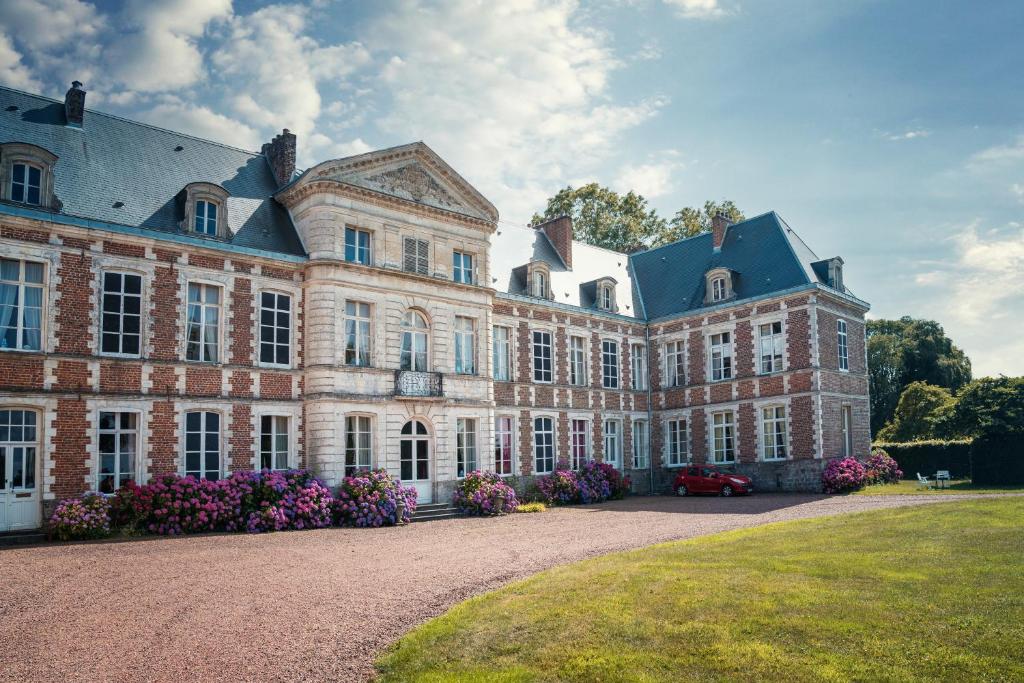 a large brick building with flowers in front of it at Chambres d'hôtes & Gîtes du Château de Grand Rullecourt in Grand Rullecourt