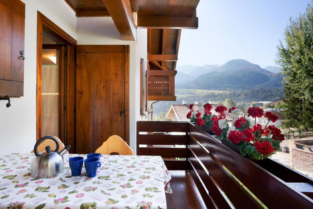 een tafel met een waterkoker op een balkon met bloemen bij La casa di Marco in Cavalese