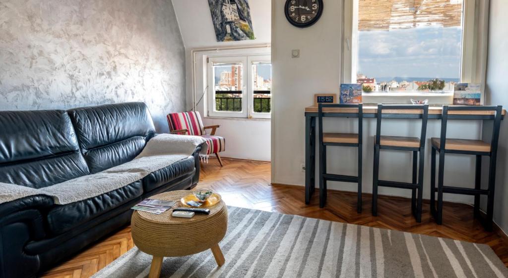 a living room with a black leather couch and a table at Apartman Centar in Niš