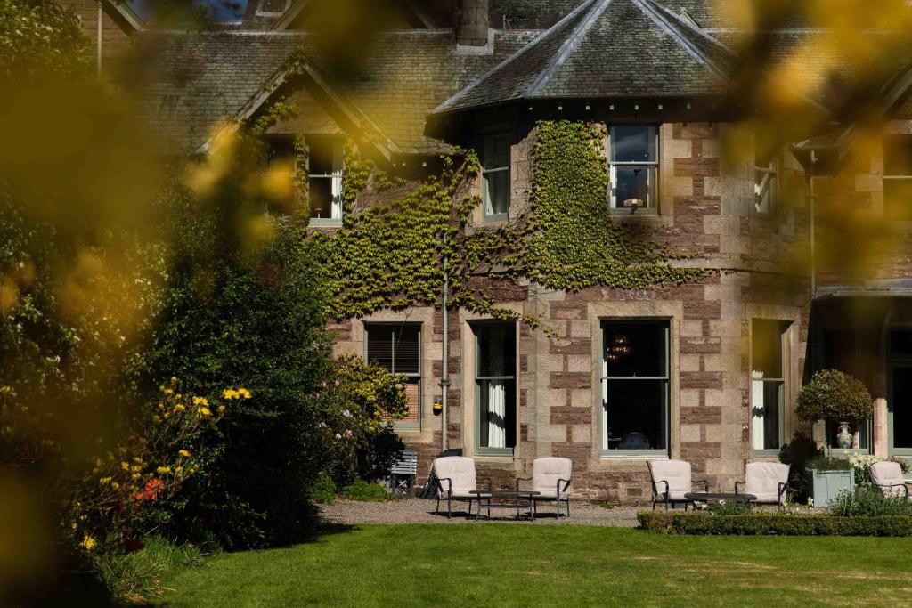 ein Haus mit Stühlen und Efeu an der Vorderseite in der Unterkunft Cromlix in Kinbuck