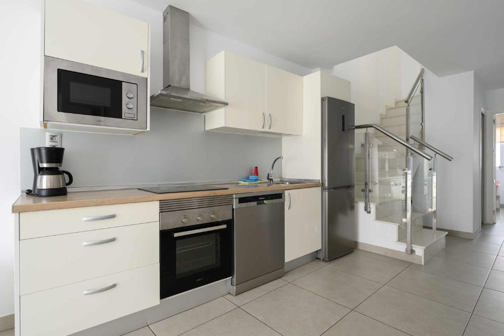 a kitchen with white cabinets and a stove and a microwave at Canteras Suites in Las Palmas de Gran Canaria