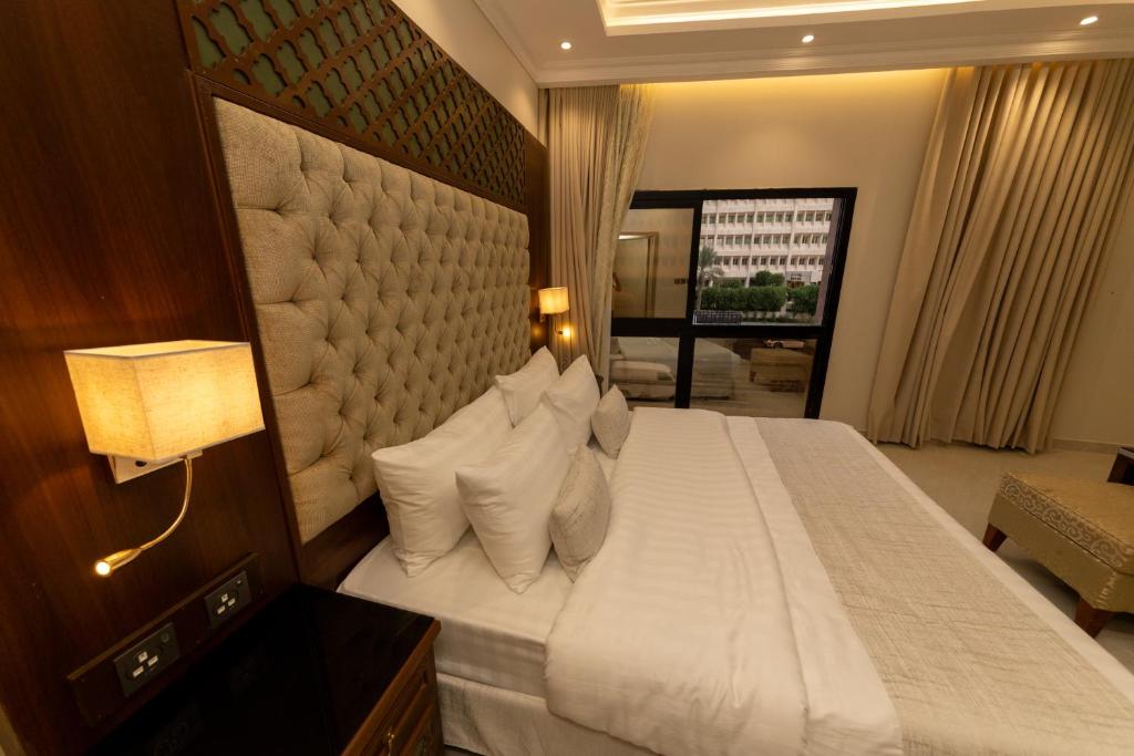 1 dormitorio con 1 cama blanca grande con almohadas en Burj Al Hayat Furnished Suites - Al Malaz, en Riad
