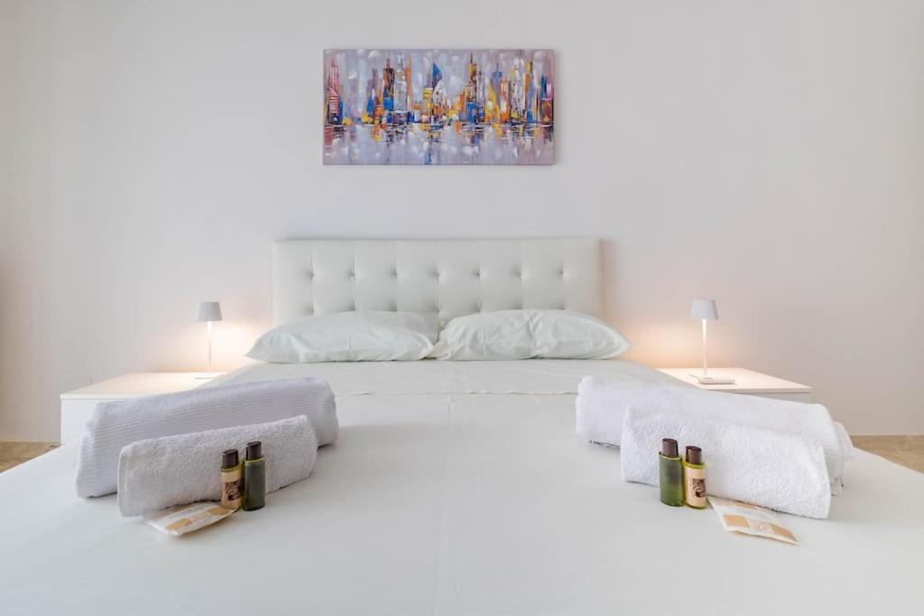 um quarto com uma cama branca e toalhas em [Apt Green Park] ¤ Best Airport Accommodation ¤ em Bitonto