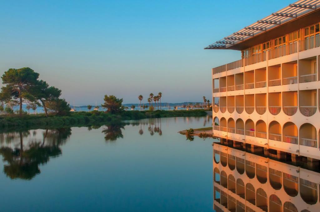 un bâtiment à côté d'une masse d'eau dans l'établissement Hotel Club Le Plein Sud Vacances Bleues, à Hyères