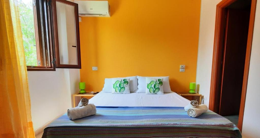 ein Schlafzimmer mit einem Bett mit einer orangefarbenen Wand in der Unterkunft B&B Demarete sullo Ionio in Arenella