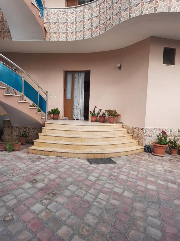 a building with stairs and potted plants on it at The quiet house in Durrës
