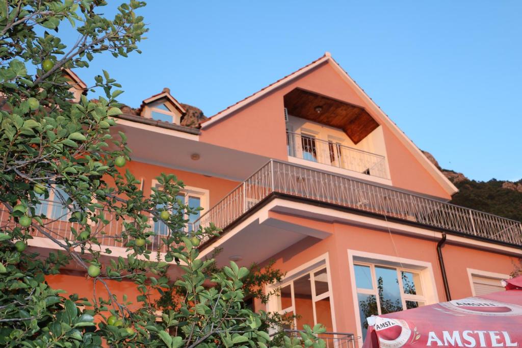 an orange house with a balcony and an umbrella at Villa Duka in Krujë