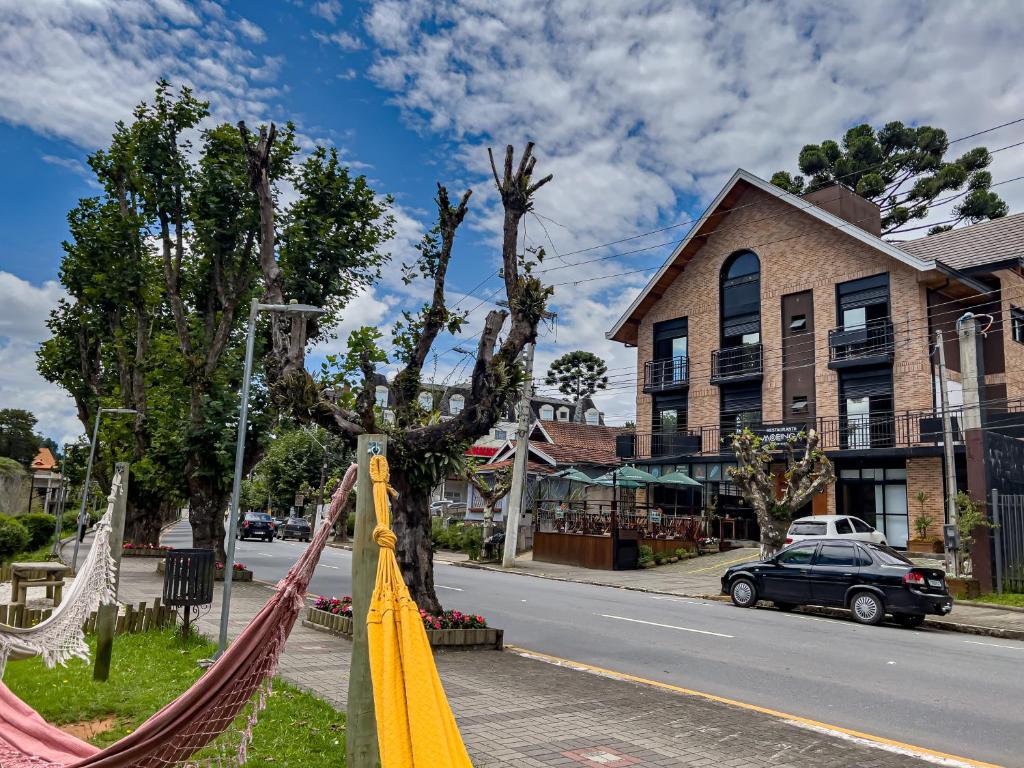 a street with a tree with hammocks and a car at Parador Campos do Jordão Em Vila Capivari in Campos do Jordão