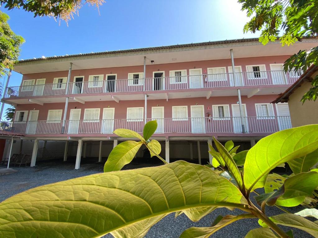 ein großes rosafarbenes Gebäude mit weißen Balkonen in der Unterkunft HOTEL ALAMEDA in Várzea Grande