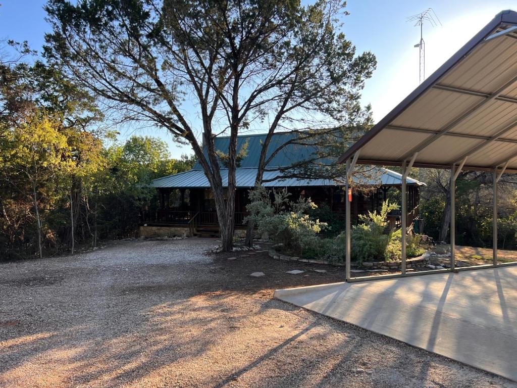 uma casa com uma árvore no meio de uma entrada em Lake Whitney Log Cabin em Lakewood Harbor