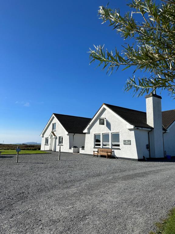 una casa blanca con un banco delante en Grianaig Guest House & Restaurant, South Uist, Outer Hebrides, en Daliburgh